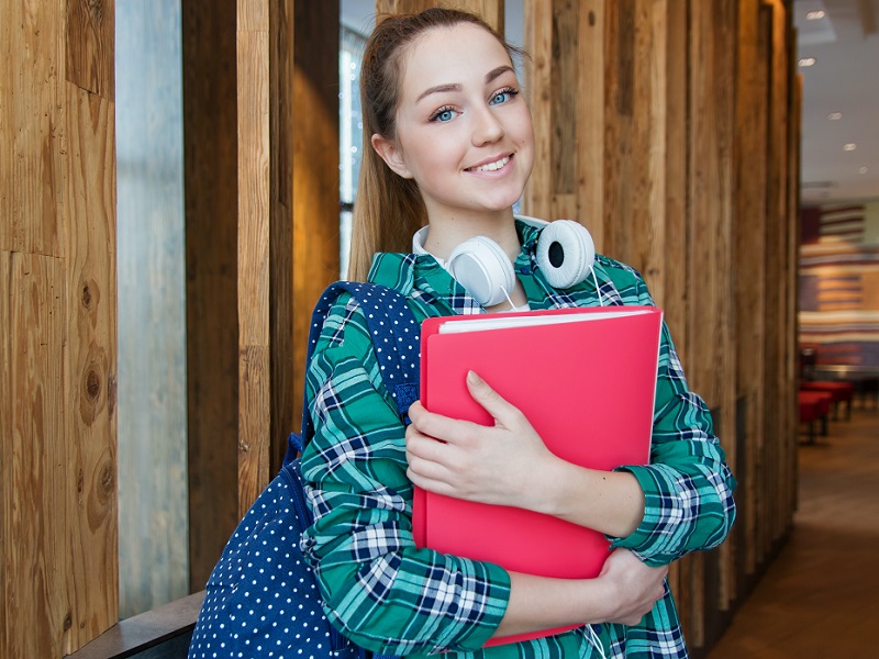 woman-standing-in-hallway-while-holding-book-1462630